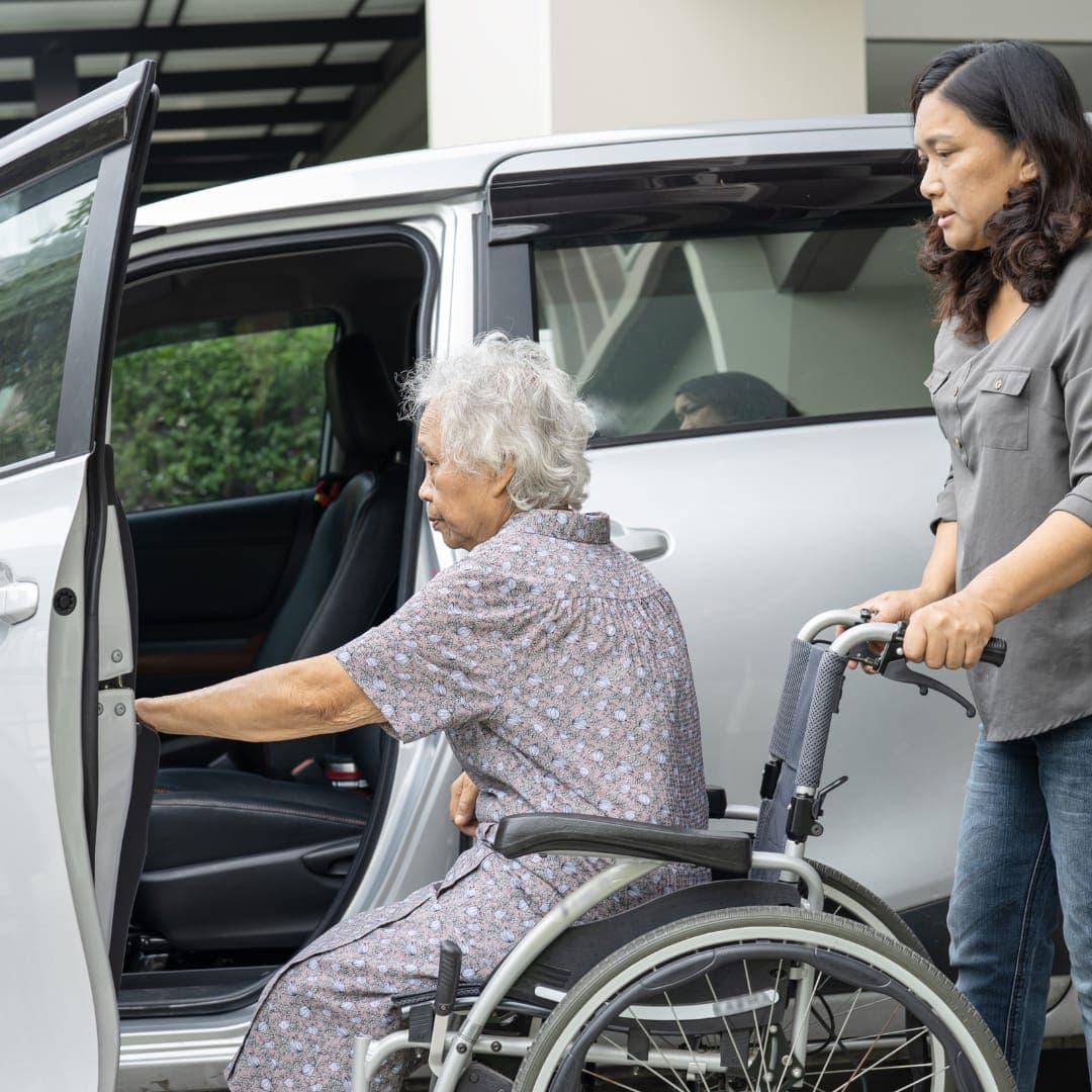 A helper with a wheelchair beside an open car door